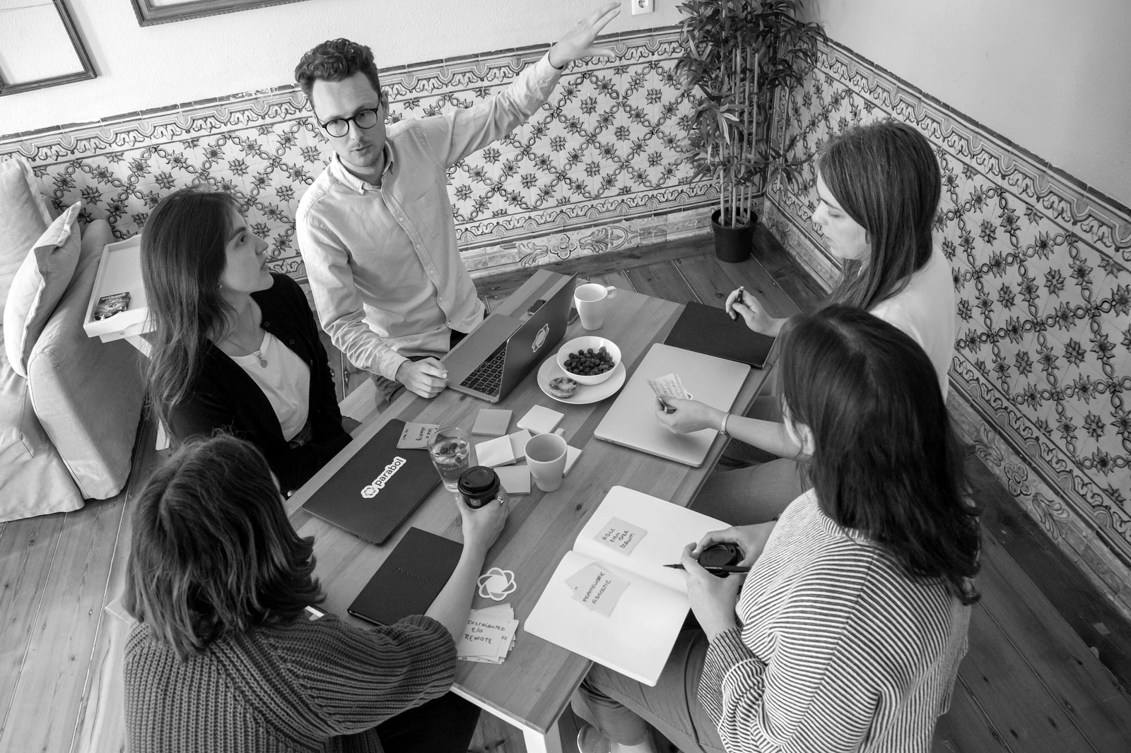 a group of people sitting around a wooden table. Photograph accompanying Velaharra’s creative proximity guide.