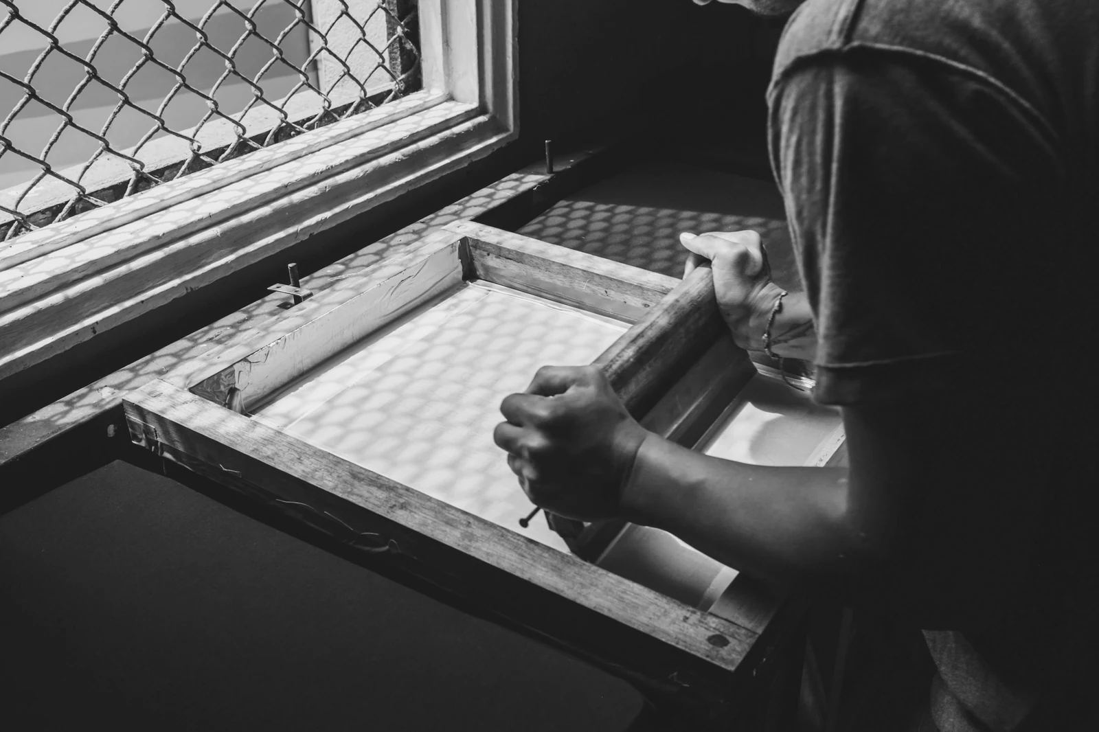 man holding printing screen near white window. Photograph accompanying Velaharra’s cultural relevance for brands guide.