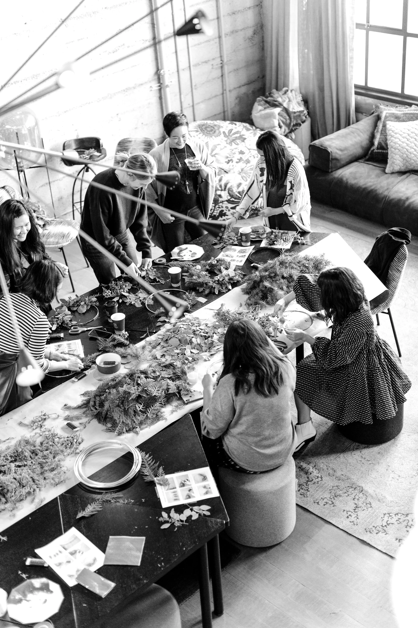 women crafting with greenery at workshop table. Photograph accompanying Velaharra’s creative community guide.